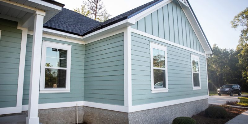An updated exterior of a home featuring light green siding and white trim, showcasing a modern and inviting appearance.